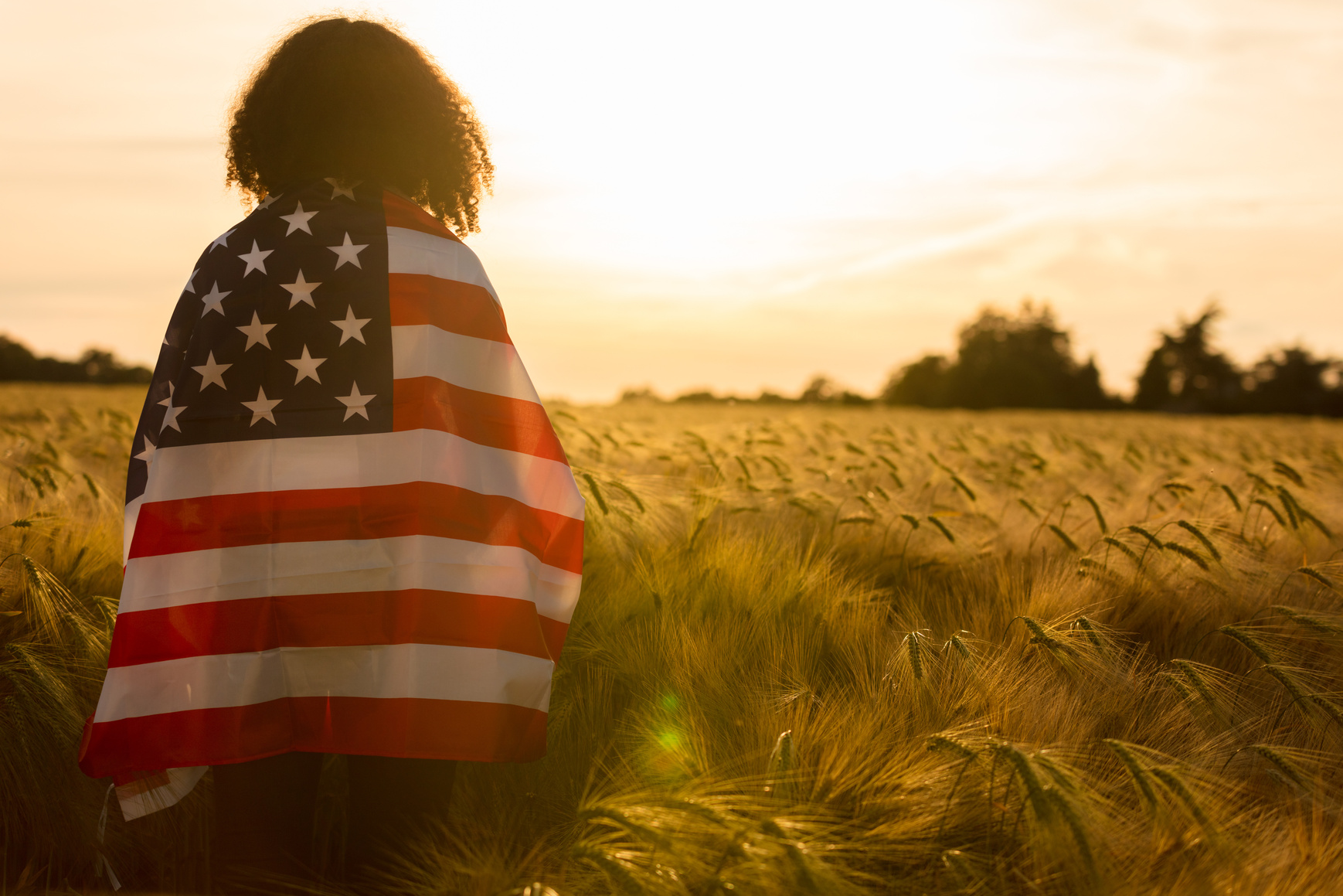 Girl Teenager Wrapped in USA Flag in Field at Sunset
